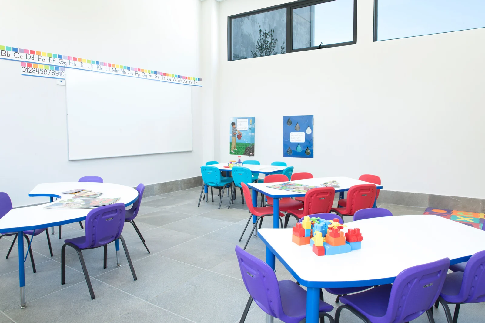 Classroom with colorful tables and chairs, a whiteboard and an alphabet on the wall