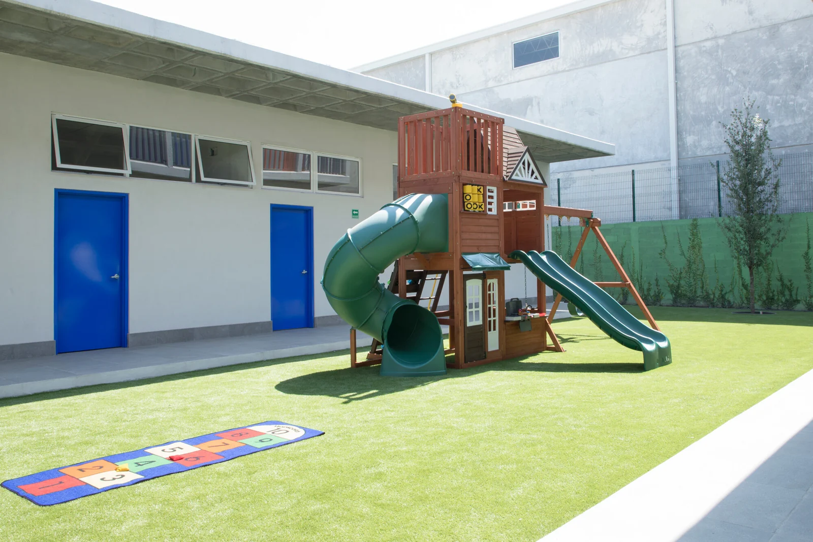 Courtyard with artificial turf and a play structure with a slide