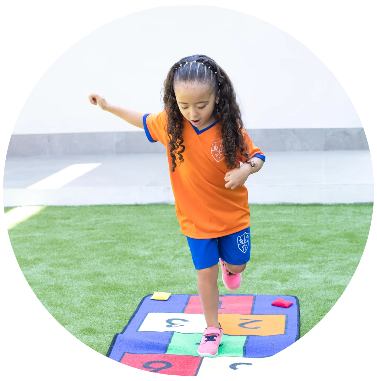 Instituto San Gerardo girl playing hopscotch on a mat in the yard
