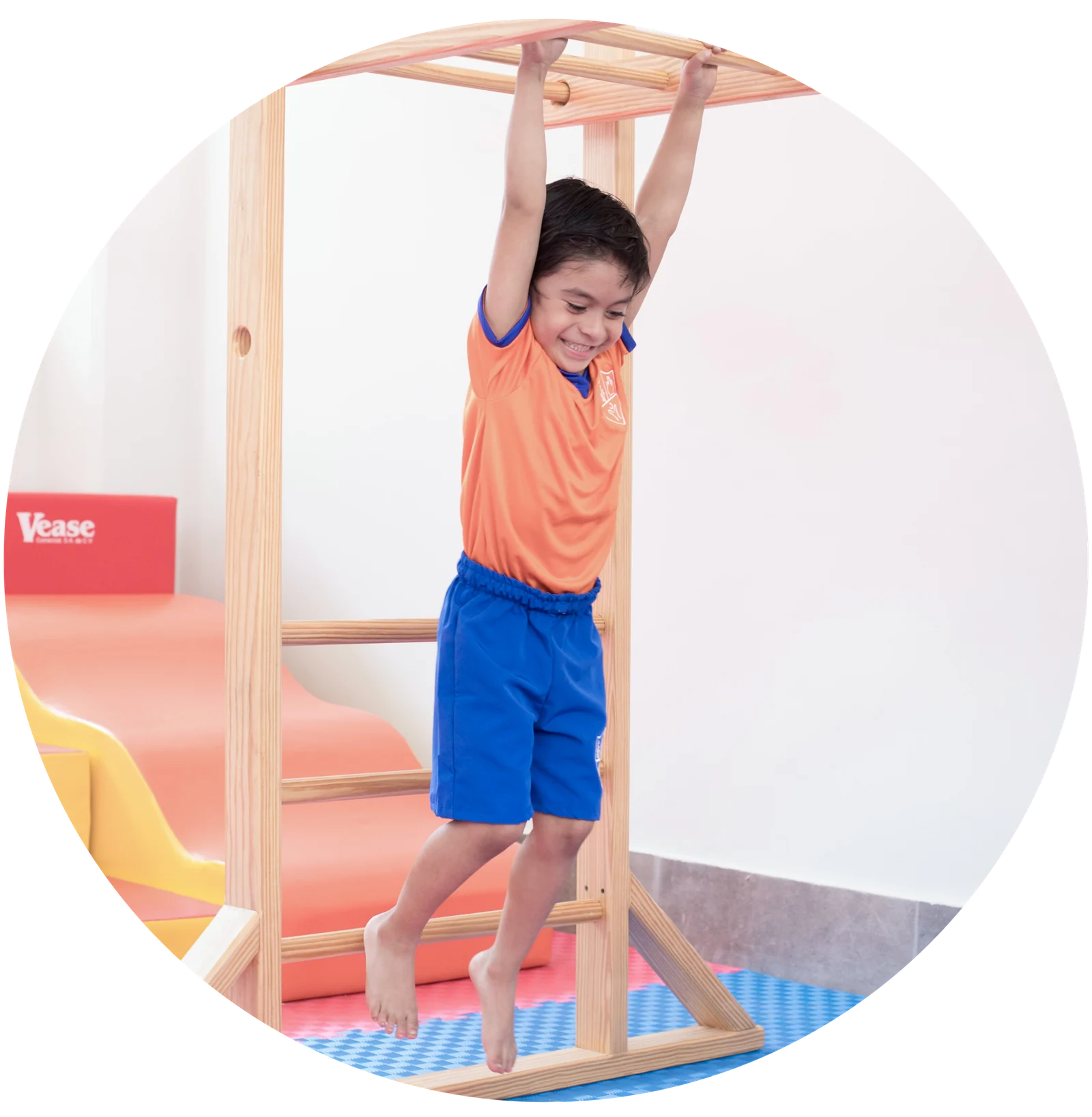 Smiling preschool child with arms raised, wearing an orange and blue uniform
