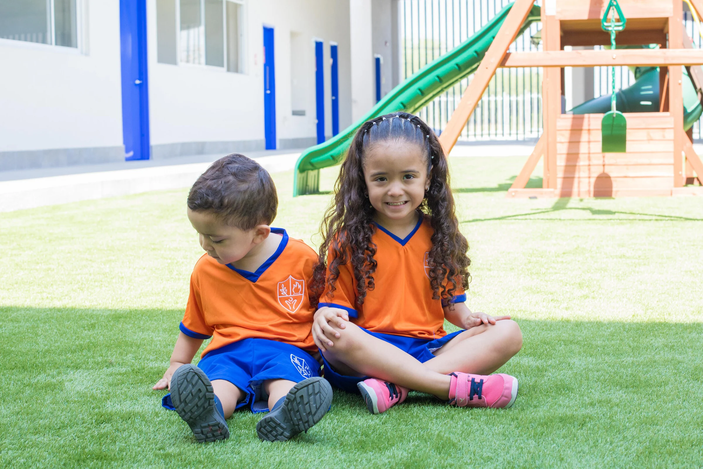 A girl and a boy from Instituto San Gerardo sitting on the grass